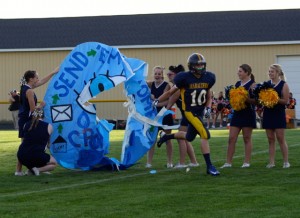 Full of excitement, Senior Travis Delaney runs through the hoop that the varsity cheerleaders made for the game against Cheasining. The  varsity football team is away this week against their rivals the Lancers of Bullock Creek. | Photo by Michaela Post