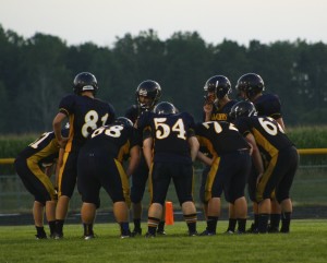 The JV football team huddles to prepare for the next play. | Photo by Allison Patterson